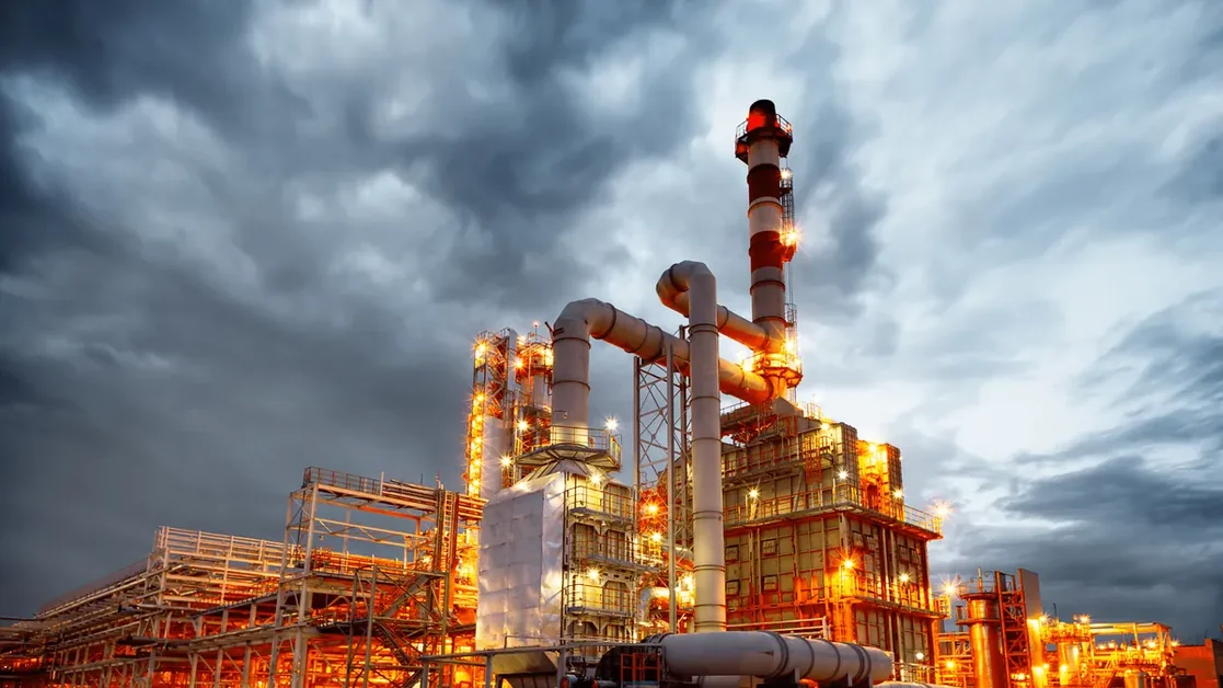 Planta petroquímica iluminada sob céu nublado