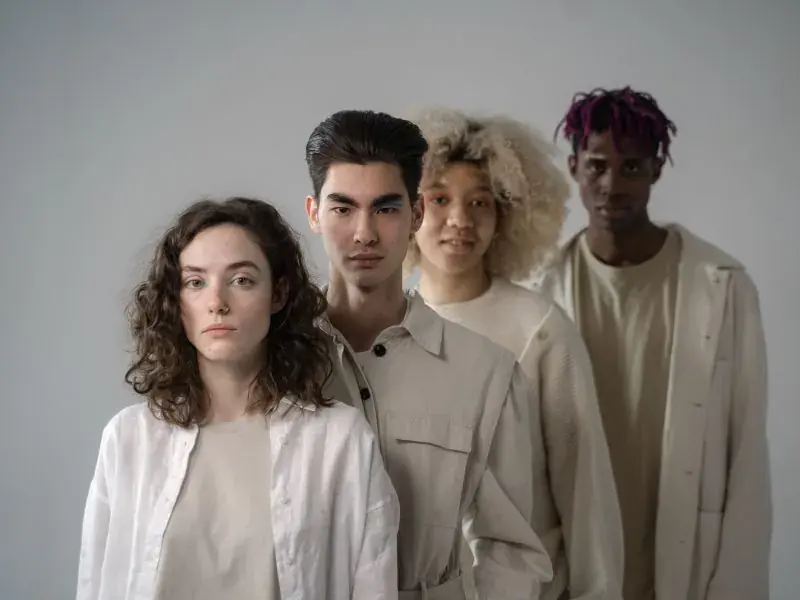 Grupo de jovens com roupas em tons neutros posando em estúdio